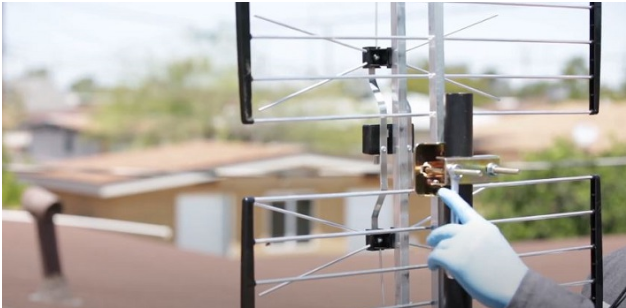 a technician wearing glove installing antenna at the rooftop