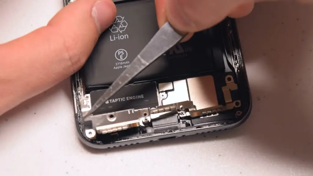 man locating iphone 11's antennae using a pointed screw