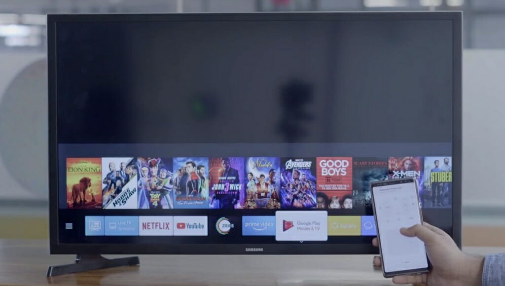 samsung big tv with a hand holding a phone beside