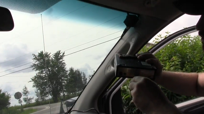 man holding the antenna box inside his car