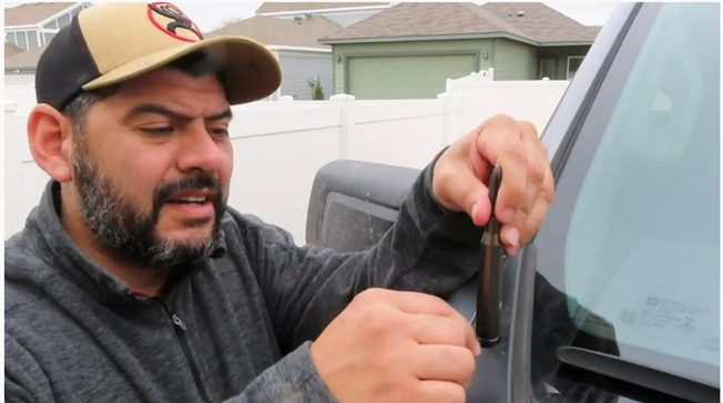 man putting a bullet antenna on his car