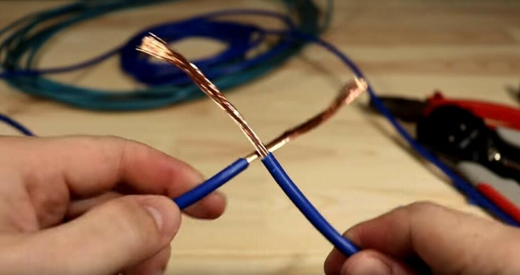 man peeling the blue wire to reveal the copper wire